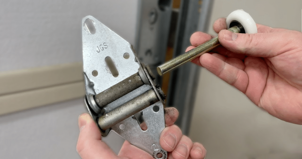 Hands hold garage door roller and hinge bracket